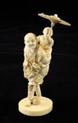 A Japanese ivory group of a grape picker and a boy, Meiji period, the man grasping a fruiting