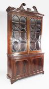 A large George III mahogany bookcase, with pierced lattice and broken swan neck pediment over