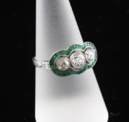 A platinum, emerald and diamond cluster dress ring, with three graduated diamonds with a total