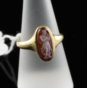 A George V 18ct gold and carnelian set cameo ring, the oval stone carved with figure of a