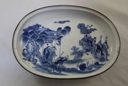 A Chinese blue and white oval dish, late 19th century, painted with a scene of figures at a gate