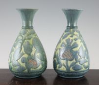 A near pair of C.H. Brannam, Barum Ware pottery vases, c.1882, decorated with blue flowers on a pale