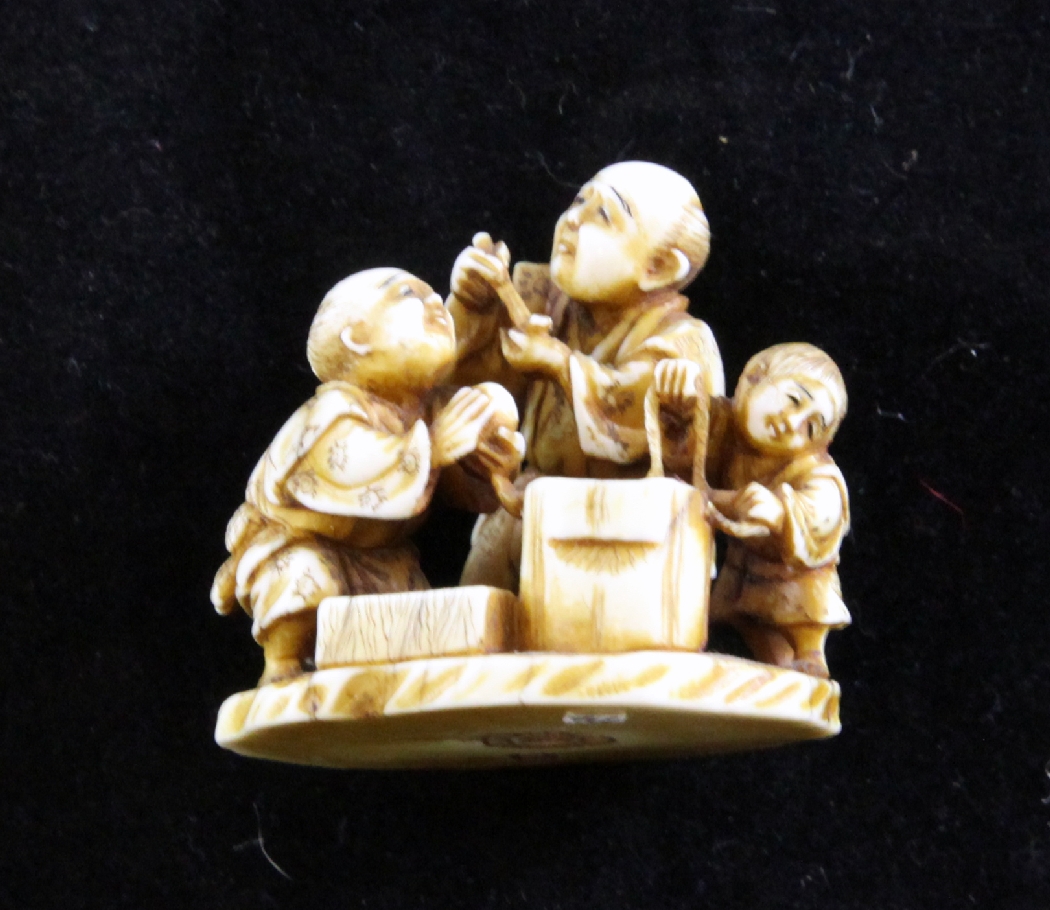 A Japanese ivory netsule of two men and a boy, early 20th century, signed Gyokusai?, 1.5in. A