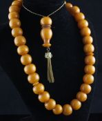 A late 19th/early 20th century single strand amber ovoid bead necklace, 31in inc. tassel. A late