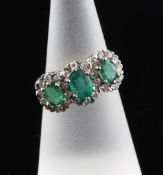 A late 1970`s 18ct gold, three stone emerald and diamond cluster dress ring, size K. A late 1970`s