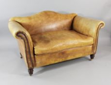 A small late Victorian leather settee, with hump back and scroll ends, on turned legs and castor
