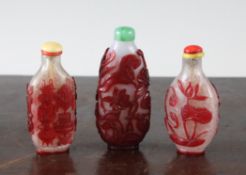 Three Chinese overlaid glass snuff bottles, two in red on a snowflake ground, the first decorated