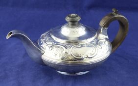 A George IV provincial silver teapot, of squat circular form, embossed with scrolls and foliage,