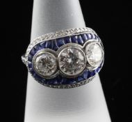 A platinum, sapphire and three stone diamond dress ring, the three central stones bordered by