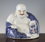 A Chinese blue and white seated figure of Budai, with enamel highlights, holding a rosary in his