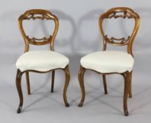 A set of six Victorian walnut balloon back dining chairs, with white calico overstuffed seats and