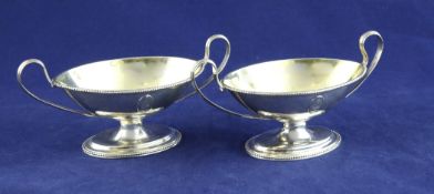 A pair of George III silver boat shaped two handled pedestal salts, with beaded borders, engraved