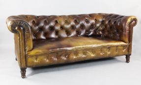 A Victorian brown buttoned leather Chesterfield settee, with scroll arms, brass studs and turned