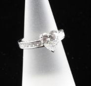 A modern platinum and heart shaped solitaire diamond ring, with scroll setting, the central stone