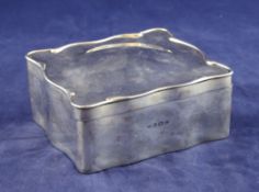 An Edwardian plain silver trinket box, of square serpentine form, the velvet lined interior with