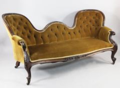 A Victorian walnut double spoonback settee with floral carved frame, buttoned upholstered and scroll