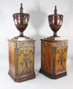 A pair of 19th century mahogany Adam style pedestal urns, the ovoid bodies with rams mask,