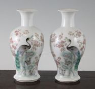 A pair of Chinese famille rose small baluster vases, each painted with a peacock perched on a rock