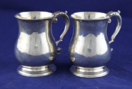 A pair of 18th century Irish silver baluster mugs, with engraved armorial and acanthus leaf capped