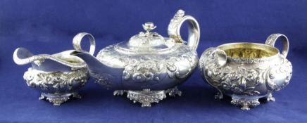 An ornate matched George IV silver three piece tea set, of squat circular form, embossed with