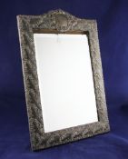 An Edwardian large repousse silver mounted easel mirror, of rectangular form, with vacant