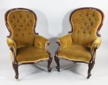 A pair of Victorian mahogany buttonback armchairs floral upholstered with scrolling arms and legs,