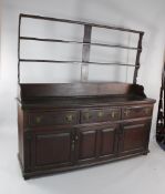 An 18th century oak dresser, with open plate rack, over three frieze drawers and two panelled doors,