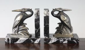 A pair of French Art Deco silvered metal bookends, each modelled with a heron, on grey marble bases,