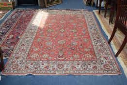 A Tabriz rug, with field of scrolling foliage, on a coral ground, with three row border, 8ft 4in