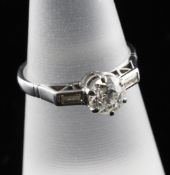 An 18ct white gold solitaire diamond ring, with baguette cut diamond shoulders, the central stone