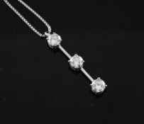 A modern platinum and three stone diamond drop pendant necklace, total diamond weight 1.022ct, on an