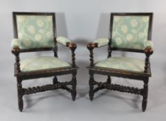 A pair of 17th century style carved oak open armchairs, with green and floral pattern upholstery,