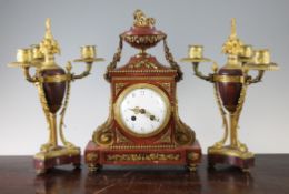 An early 20th century French ormolu mounted red marble clock garniture, of architectural form with