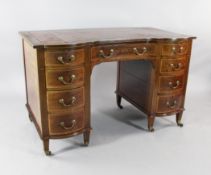 An Edwardian mahogany inverted breakfront desk, the single drawer between bow end doors, on