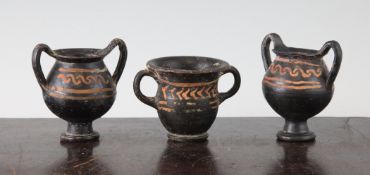 Three Greek Apulian black glazed vessels, c.4th century BC, comprising two kantharos and a krater