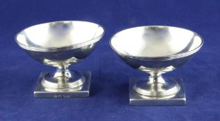 A pair of George III silver circular pedestal salts, with engraved armorial and reeded border, on