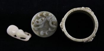 Three Chinese jades, the first a celadon disc belt ornament carved in relief with a chi-dragon,