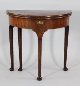 A mid 18th century mahogany demi-lune folding tea table, with turned pole legs and pad feet, W.2ft