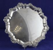 A George V silver salver, of shaped circular form, with shell and foliate scroll border, on ball