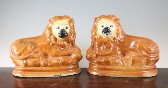 A pair of Scottish pottery figures of recumbent lions, c.1910, each with glass inset eyes, decorated