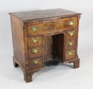 An 18th century style feather banded walnut kneehole desk, with single drawer over an arrangement of