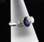 A modern platinum, sapphire and diamond three stone ring, the oval cut sapphire flanked by round cut