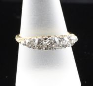 An Edwardian 18ct gold and graduated five stone diamond ring, with pierced scroll setting, the total