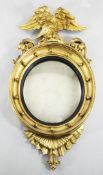 A Regency carved giltwood convex wall mirror, with eagle crest and pierced acanthus scrolls, the