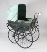 A Victorian wrought iron pram, with leather strap suspension, white ceramic handle and green watered