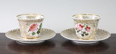 A pair of 19th century porcelain tea cups and saucers decorated with pink flowers within