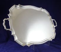 A George V plain silver two handled tea tray, of shaped rectangular form, with stepped border, James