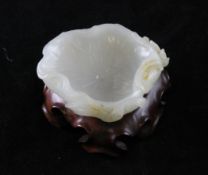A Chinese white and russet skin jade `lotus` brush washer, the curling leaf carved beneath in relief