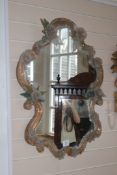 A decorative Venetian cartouche shaped mirror, with applied glass scrolls, flowerheads and leaves,