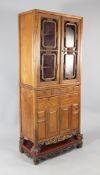A Chinese or South East Asian satinwood cabinet, fitted with a pair of glazed doors over an